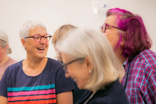 Group of people sitting together, smiling and engaged in conversation.