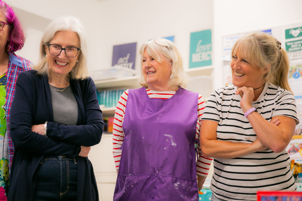 Three women standing together in a classroom setting, smiling and posing for a photo.